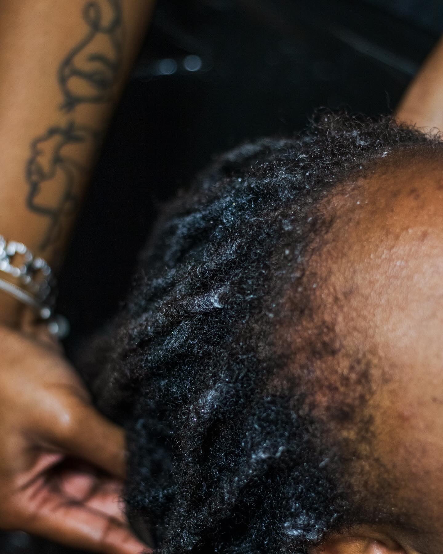 Close-up of a person's head with textured hair, focusing on the hair and skin.